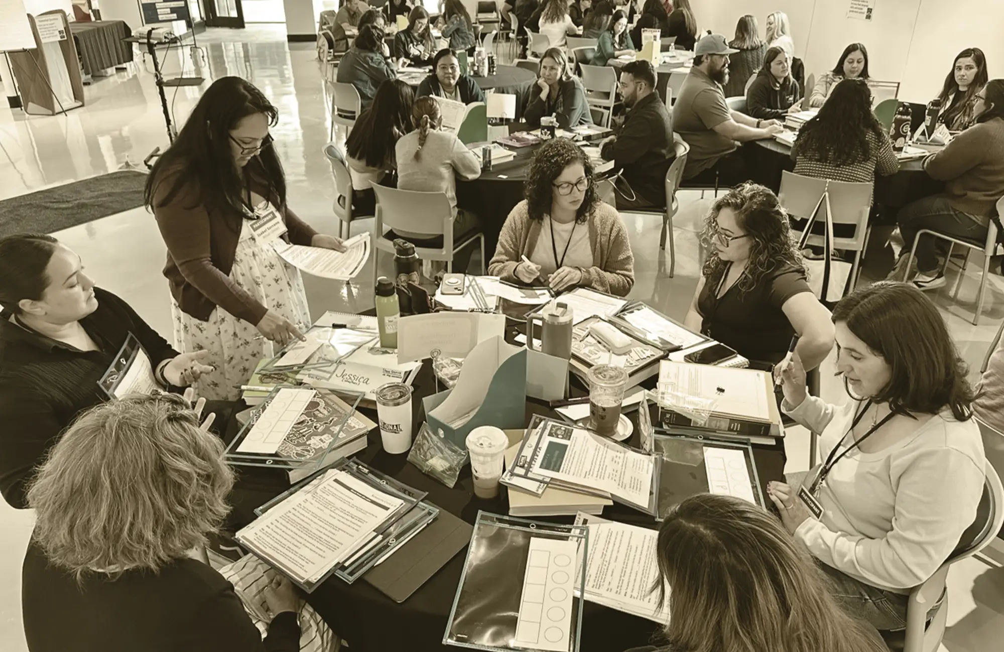 Group of educators and school staff members collaborating around large tables during a professional development workshop or training session.