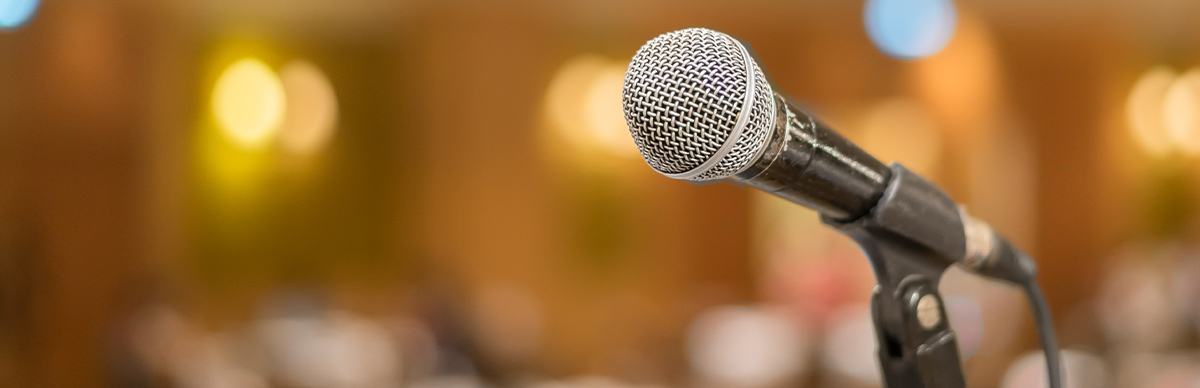 Close-up of a microphone on a stand, ready for a speaker at a public address, conference, or educational event