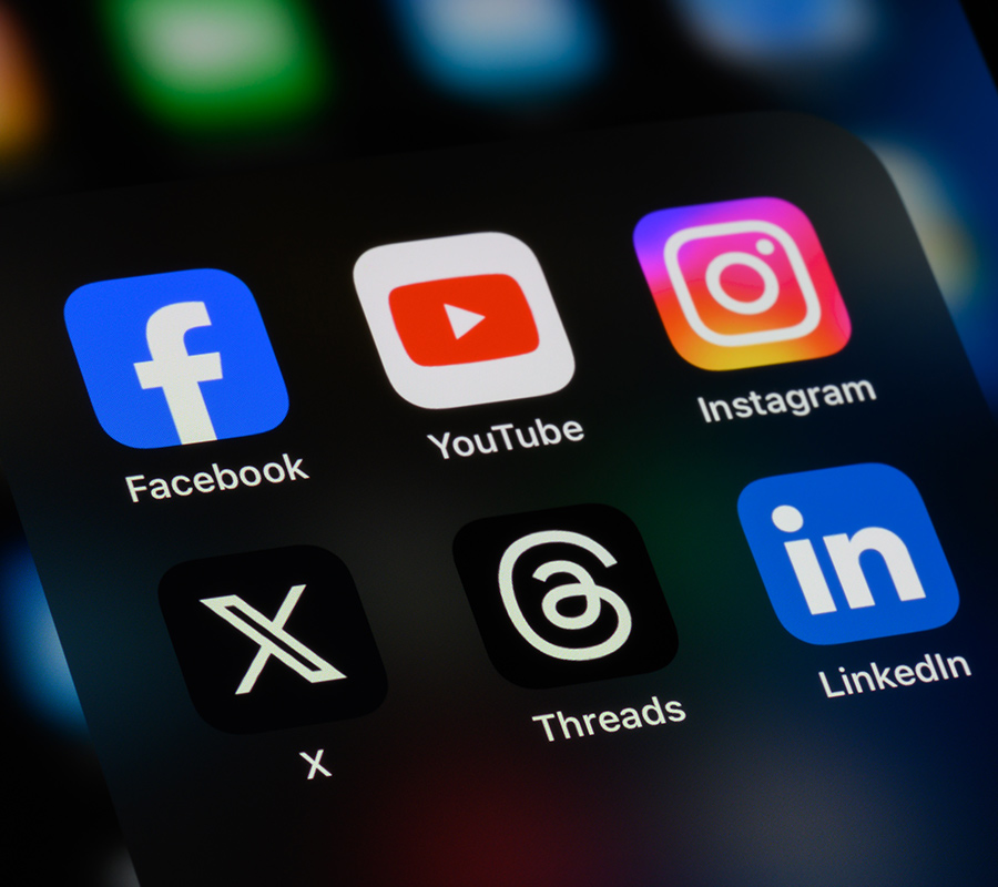 close view of a smartphone screen showing social media apps including Facebook, YouTube, Instagram, X, Threads, and LinkedIn