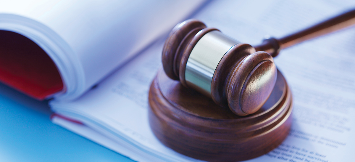 A wooden gavel rests on a sounding block over open legal documents.