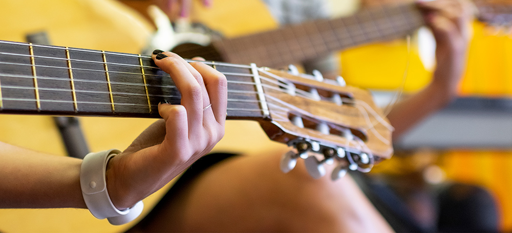 Close-up of hands playing an acoustic guitar neck during a music session.